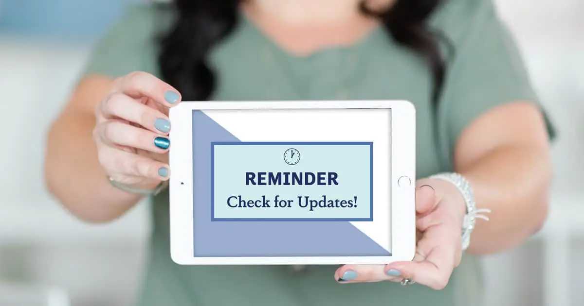 A woman holding an iPad with "Reminder: Check for Updates!" on the tablet screen.