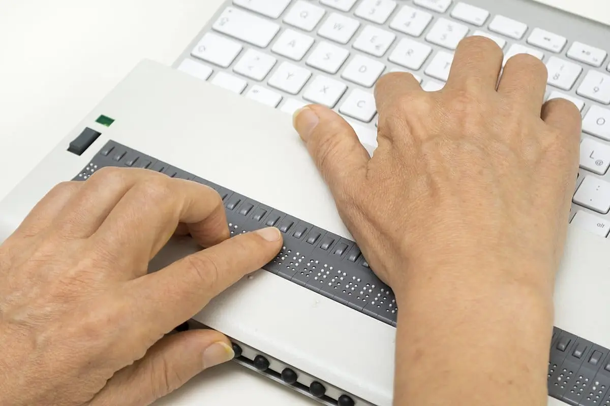Visually impaired working on computer with assistive technology; refreshable braille display.